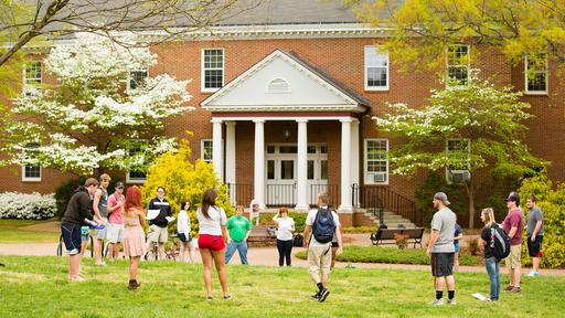 A group of Guilford College students gathers in front of Bauman Hall
