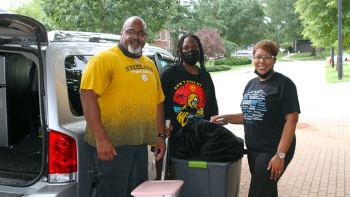 A family of three takes a break to smile at the camera during move-in.