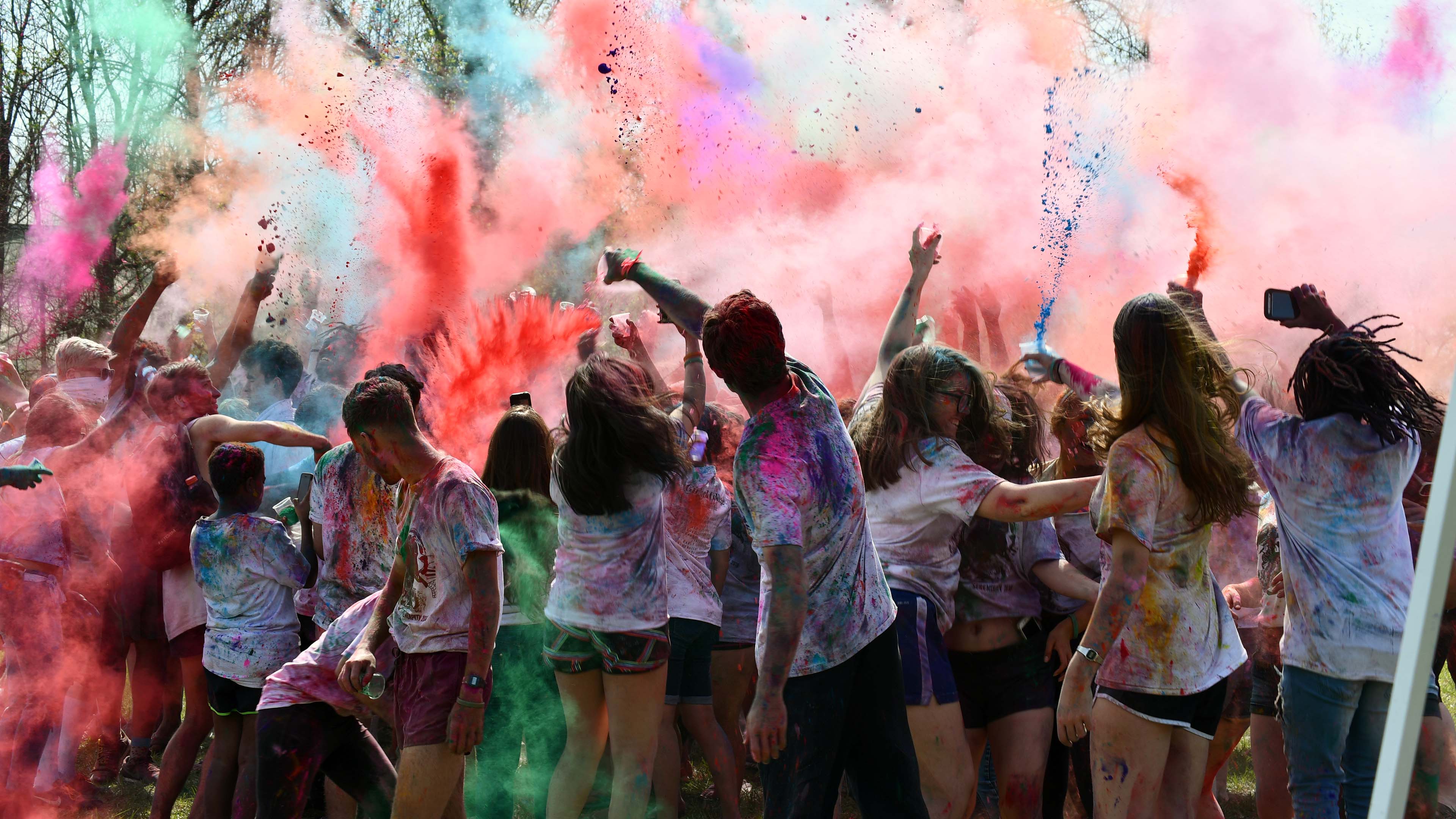 Guilford College students participate in the annual Serendipity colorfest, throwing colored powder into the air.