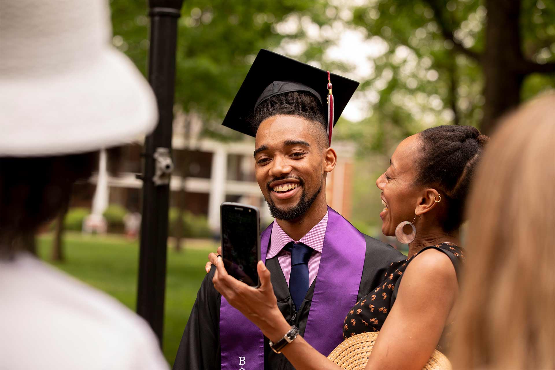 A friend shows a student a phone photo after Commencement.