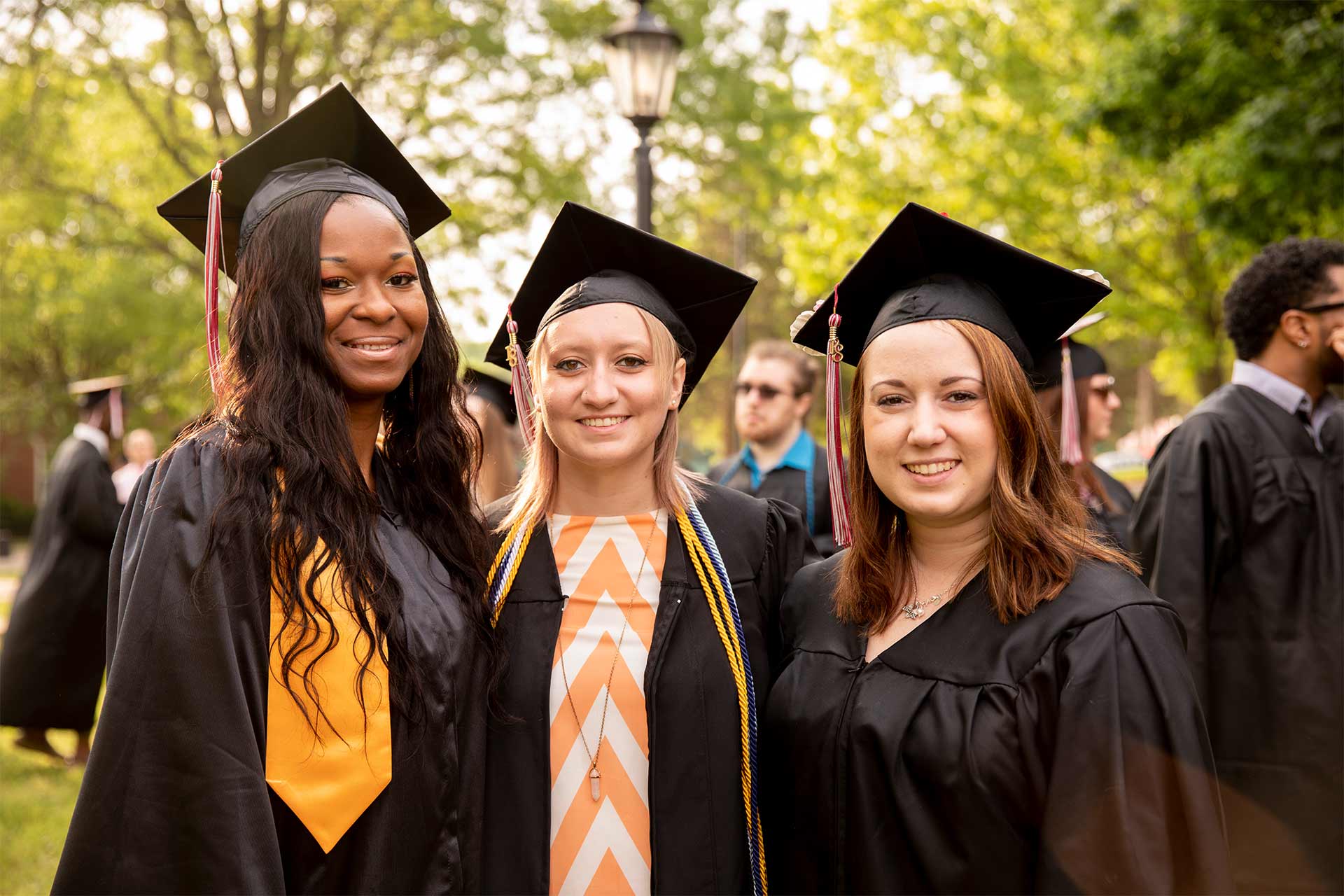 Three students take a photo together after Commencement.