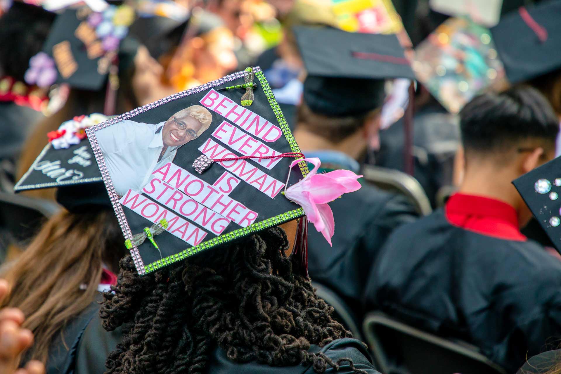 A student's mortar board reads, "Behind every woman is another strong woman."