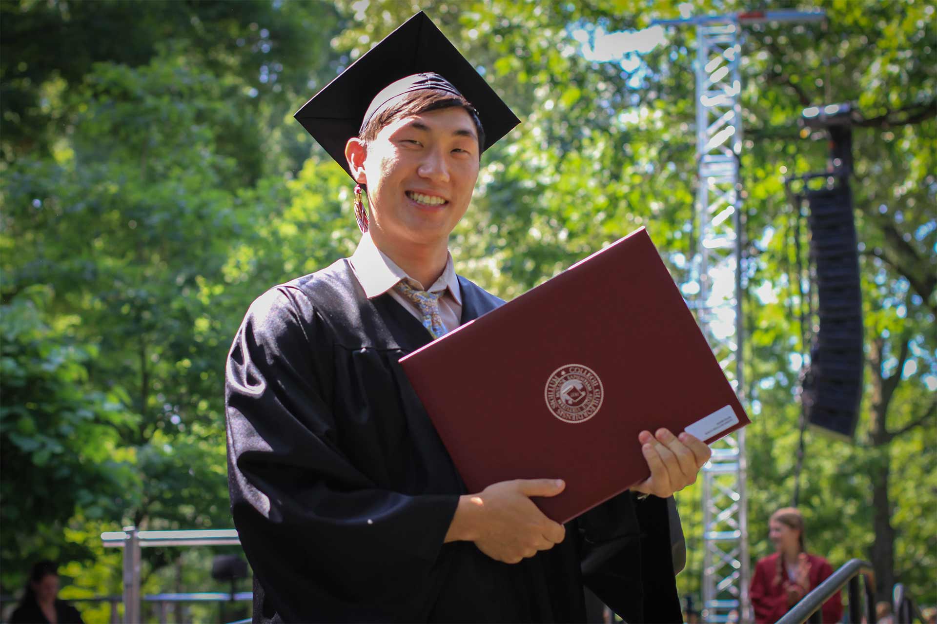 A graduate poses with his diploma.