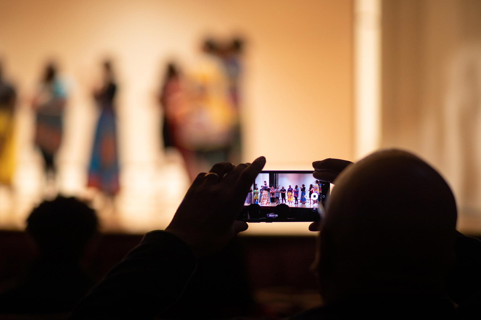 Audience members use their phones to capture the Voices of Victory Gospel Ensemble performing.