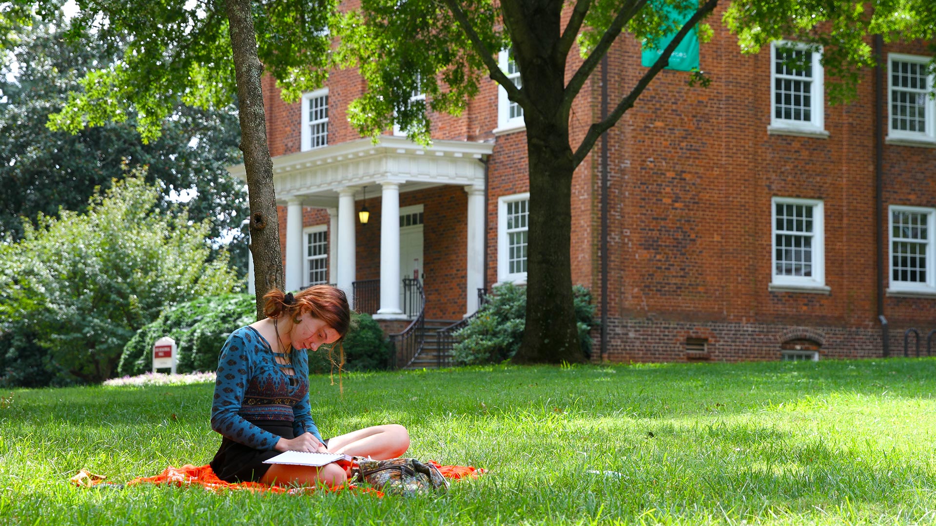 A student takes a study break on the Quad in front of Duke Hall.
