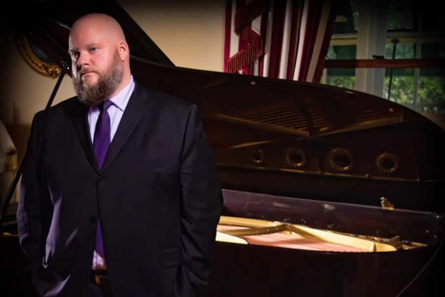 Guilford College alum and Music major Matt Reid 16 stands in front of an open piano.