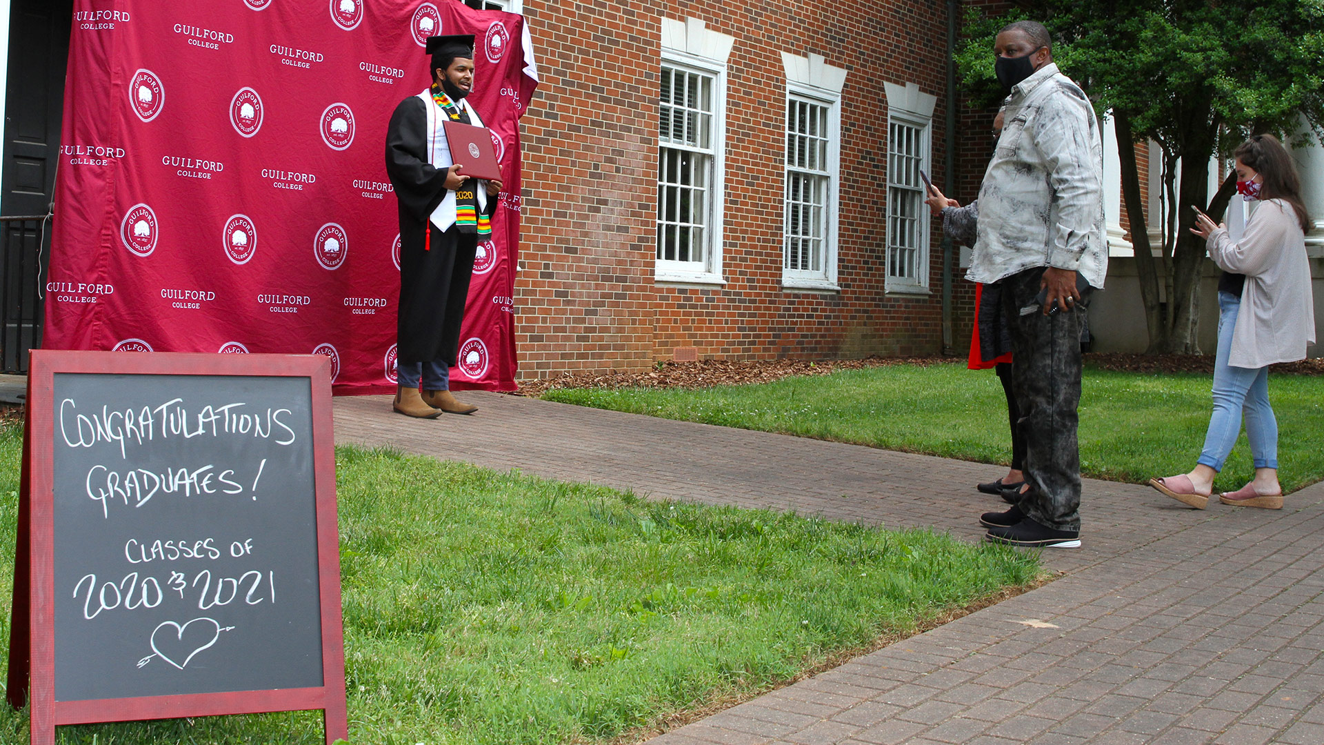 Daniel Bratcher '20 takes a photo in front of the Guilford College backdrop.