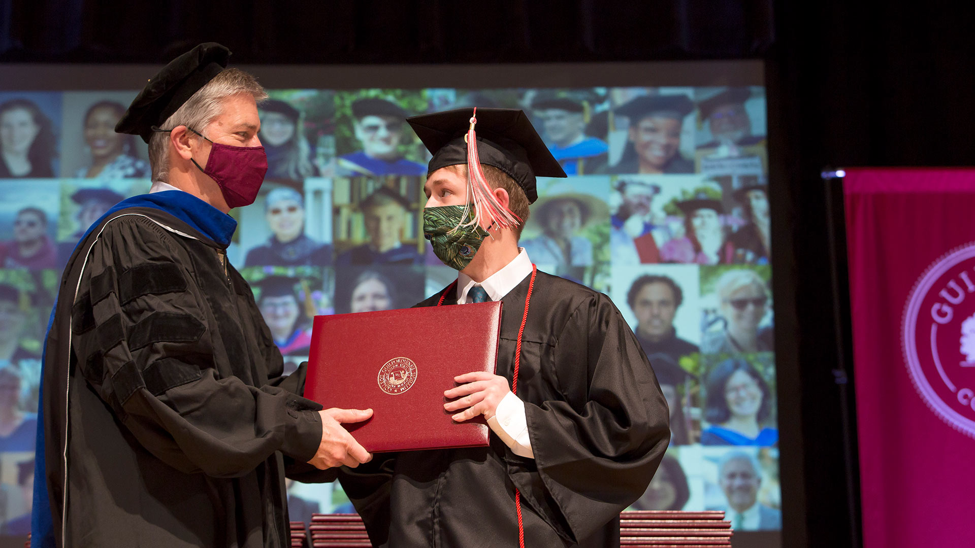 President Jim Hood '79 hands a diploma to a graduate on stage.