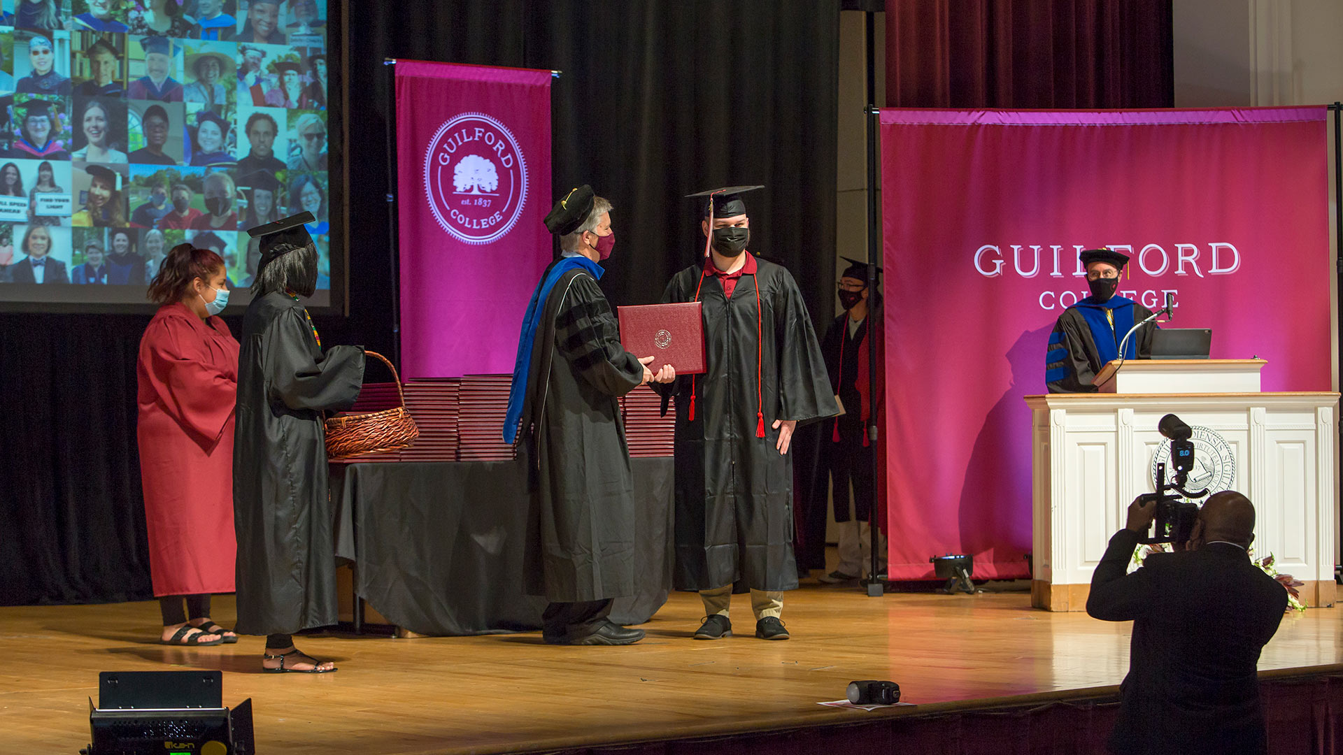 A graduate stands on the stage in Dana Auditorium.