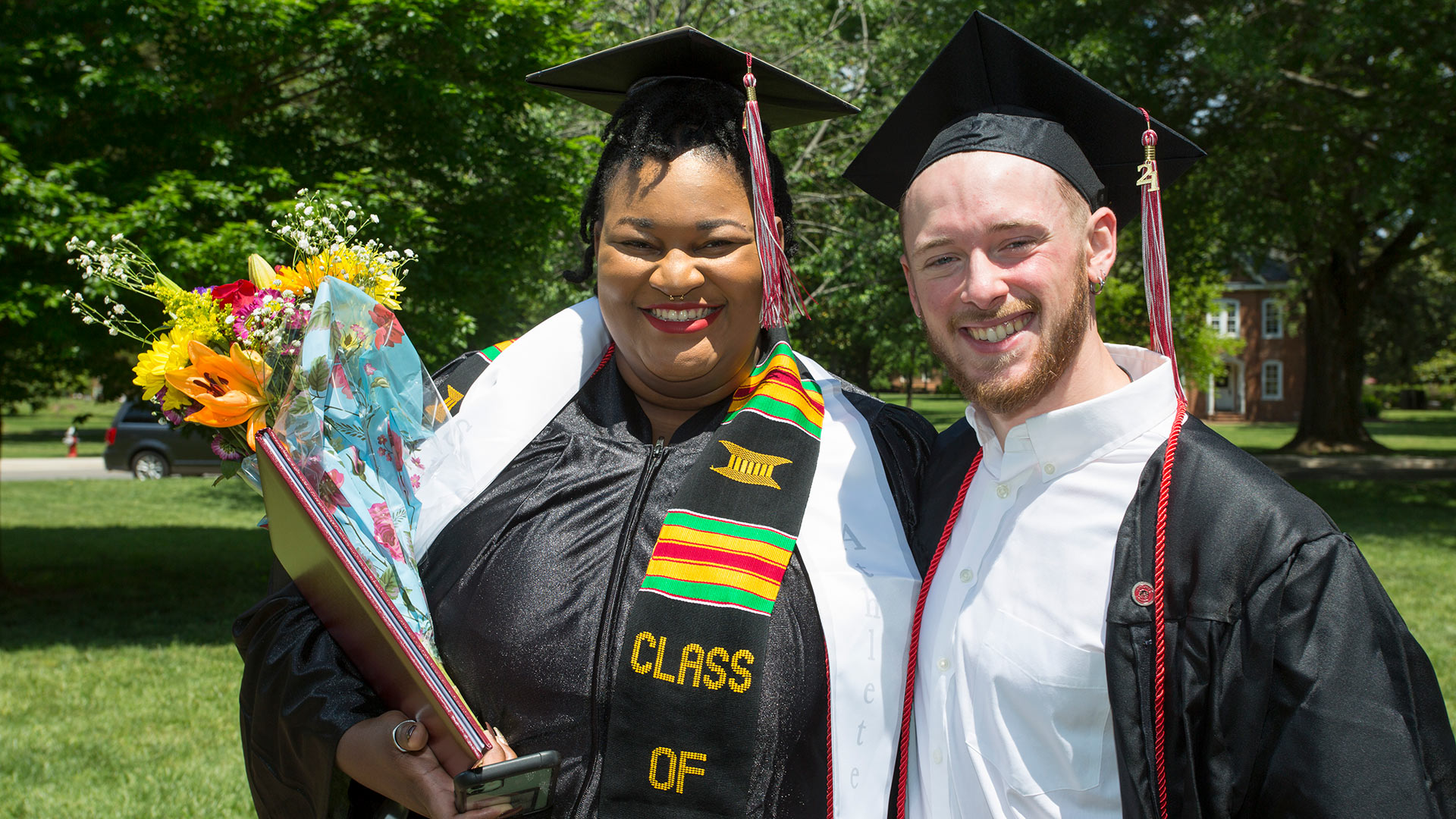 Two 2021 graduates smile as they take a photo together.