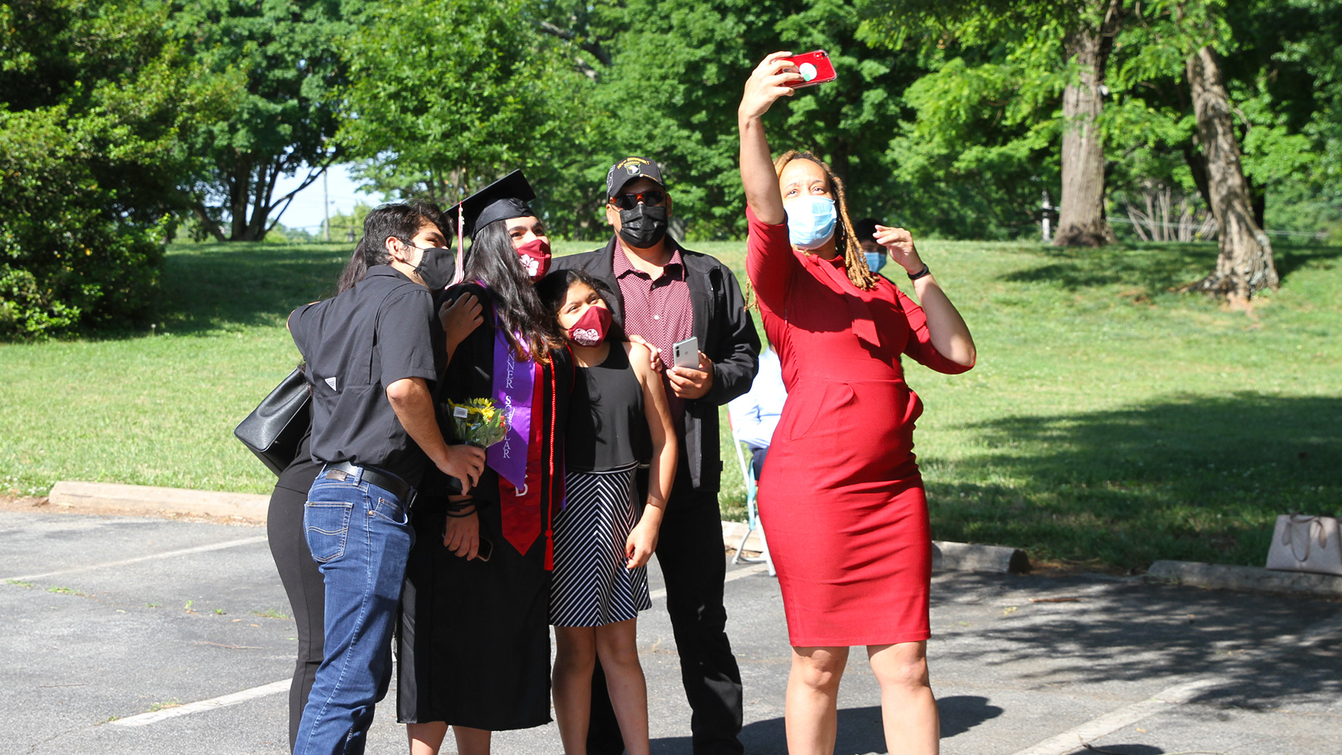 A staff member takes a group selfie with students and graduates at Commencement 2021.