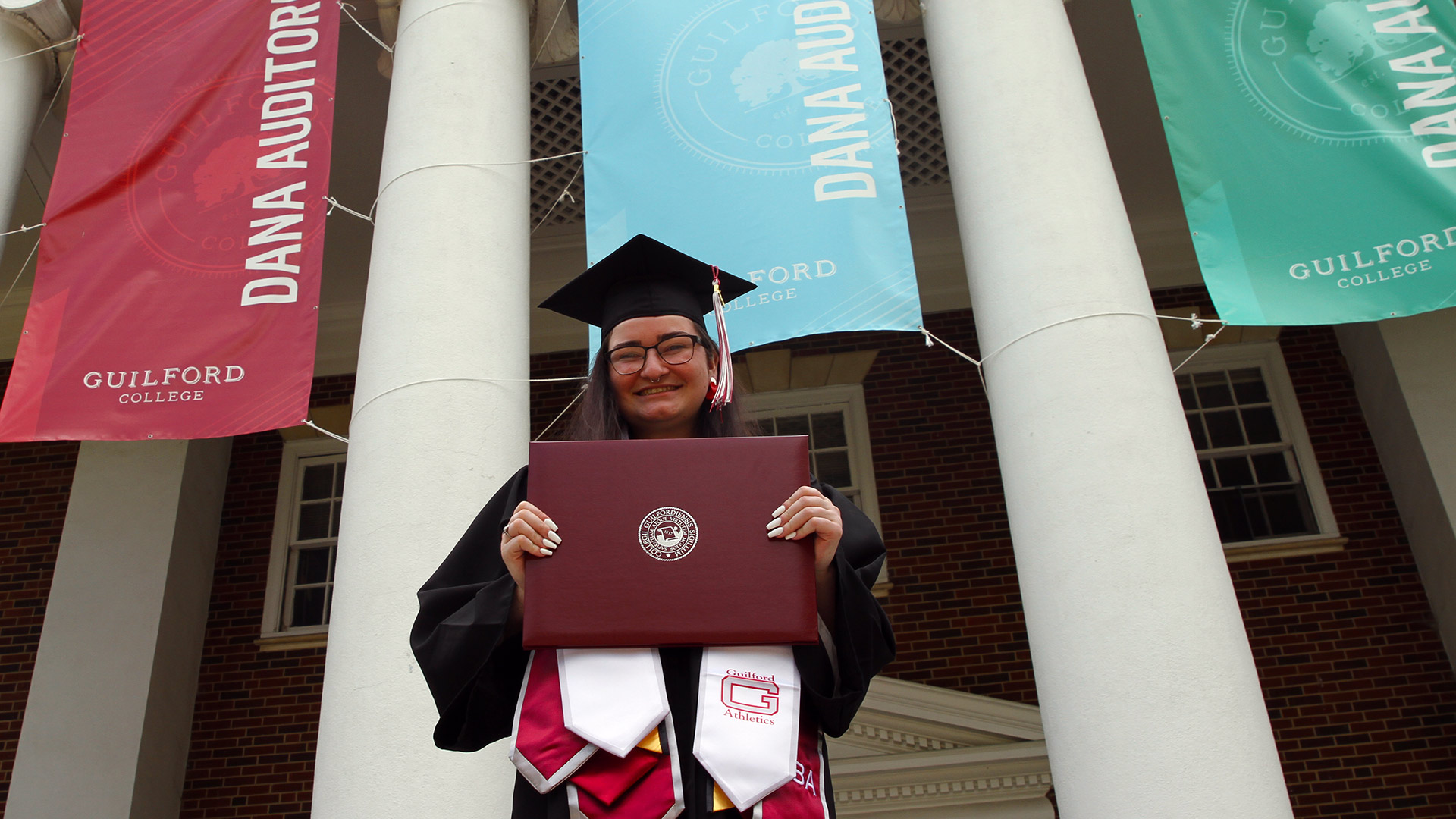 A 2021 graduates holds their diploma outside Dana Auditorium.