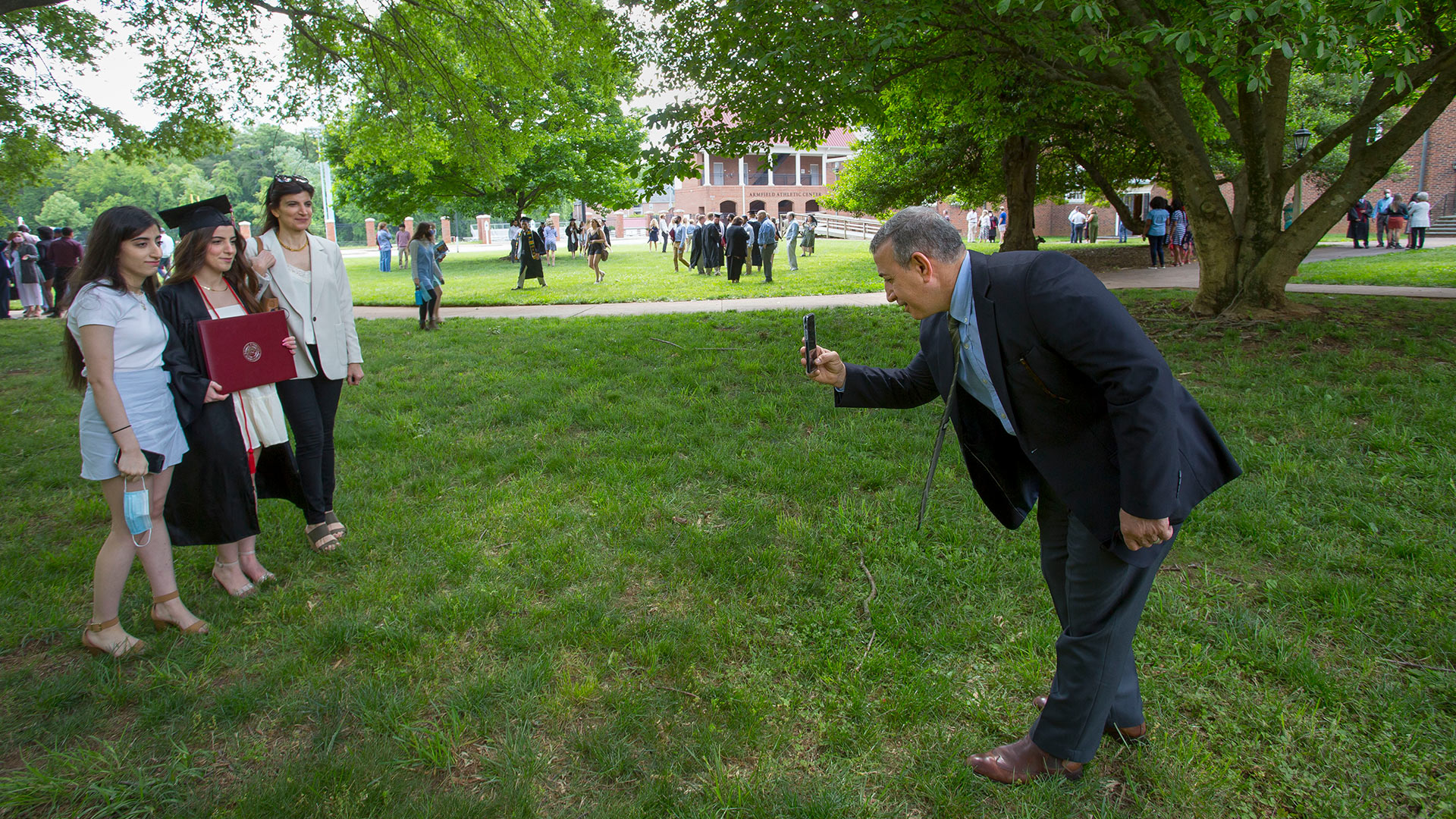 A friend takes a photo of their graduating senior outdoors.