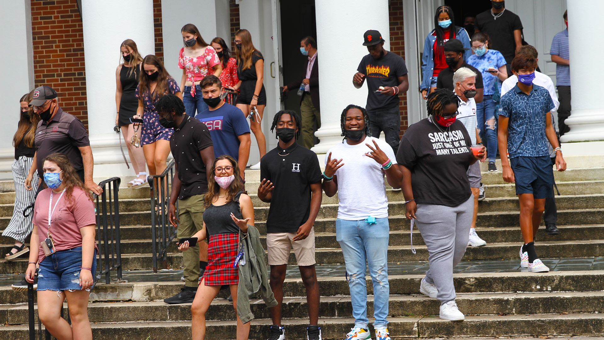 The audience exits Dana Auditorium after Convocation, and a group of three students smiles at the camera.
