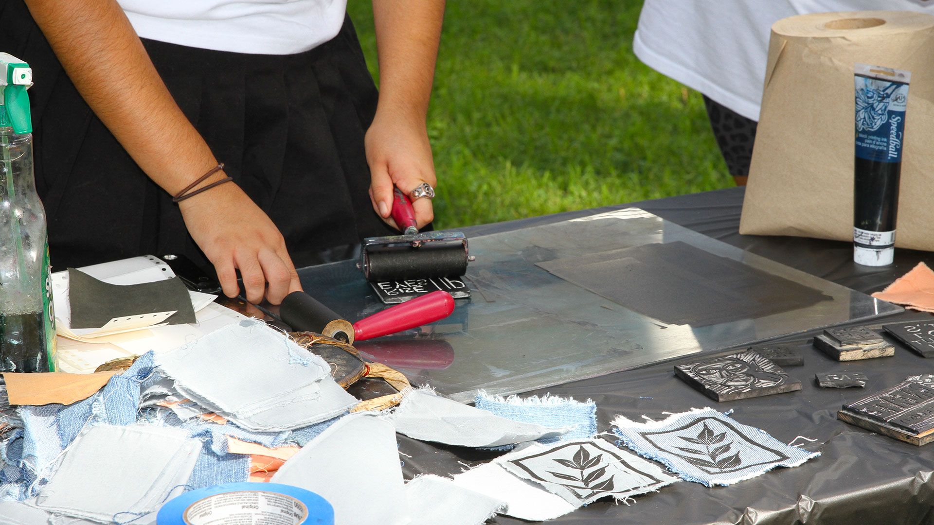A student applies paper to a decal using a roller at Free Press.