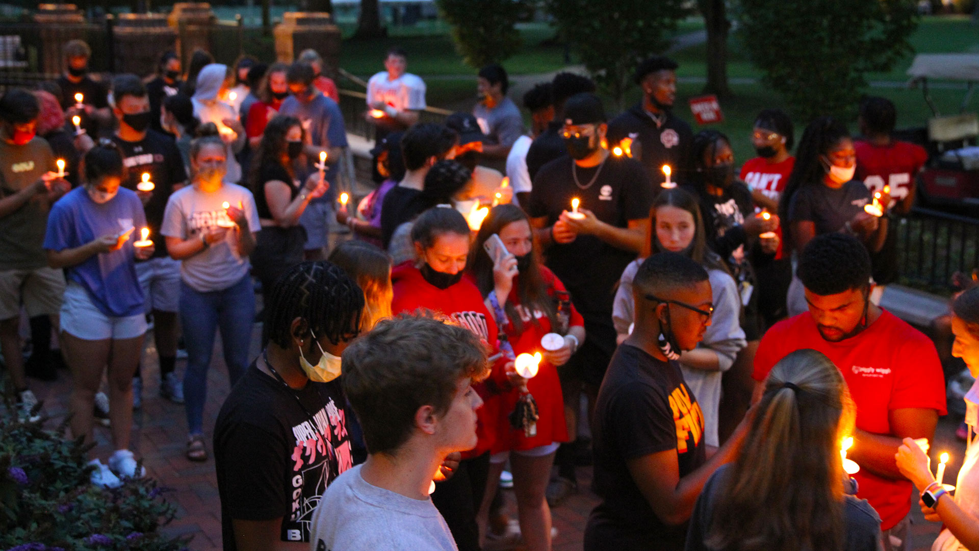 Founders Patio is filled at dusk with a large group of students, all holding their lighted candles at the ceremony.