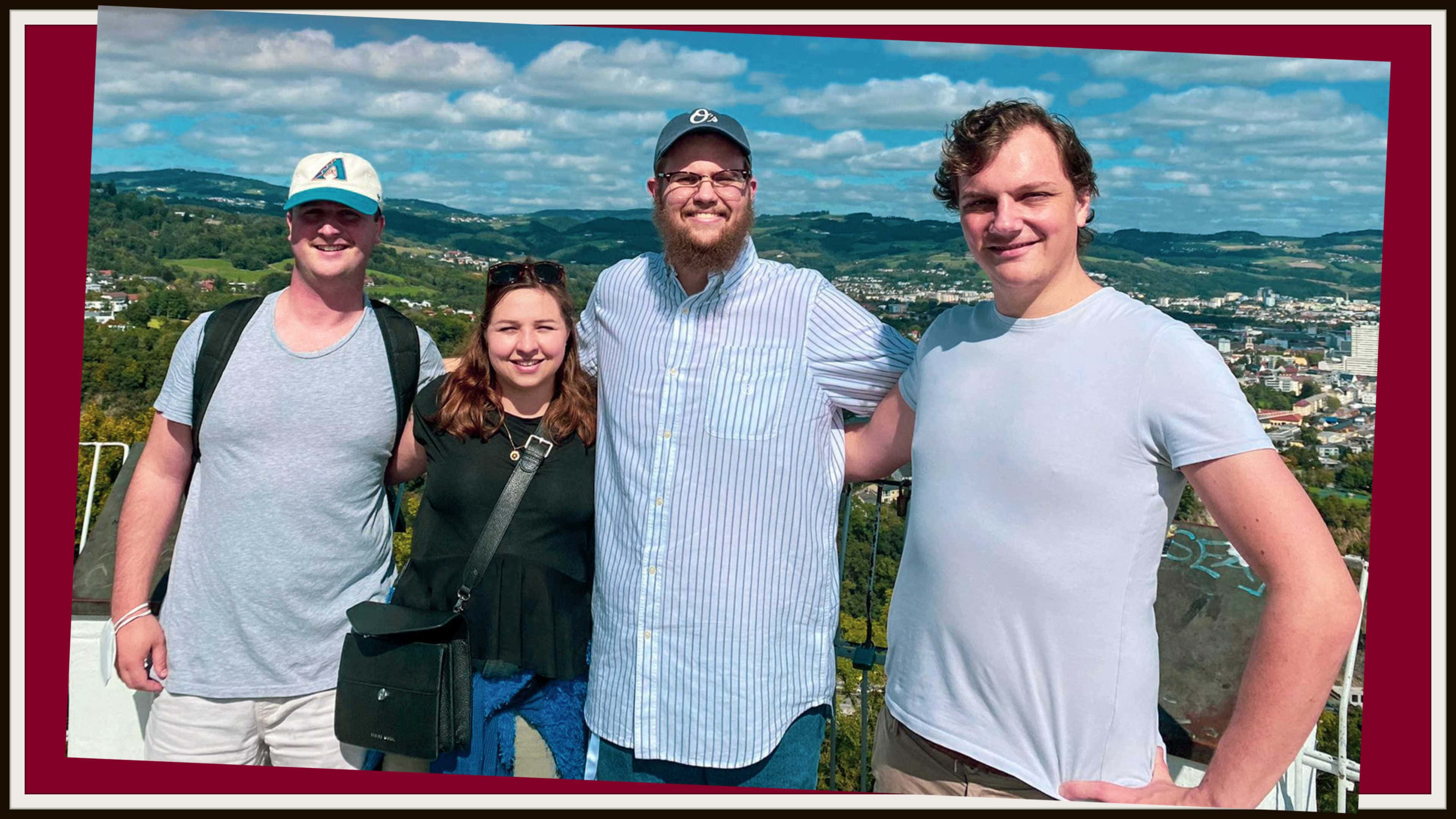 Show from left are Ian, Eva (Ian's wife), Dylan, and Caleb. They're standing outdoors with Austria's landscape behind them.