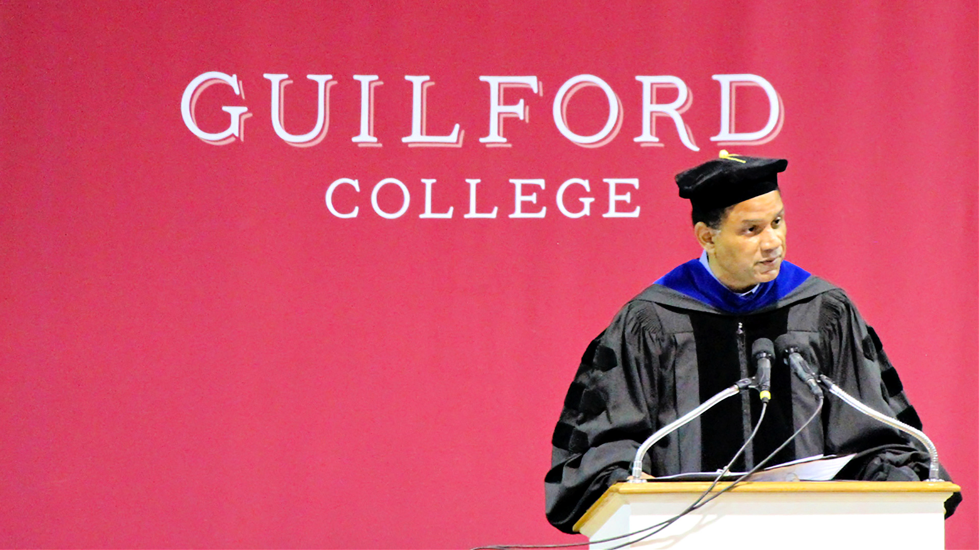 Guilford College President Kyle Farmbry speaks from the podium to open his first Commencement ceremony at Guilford.