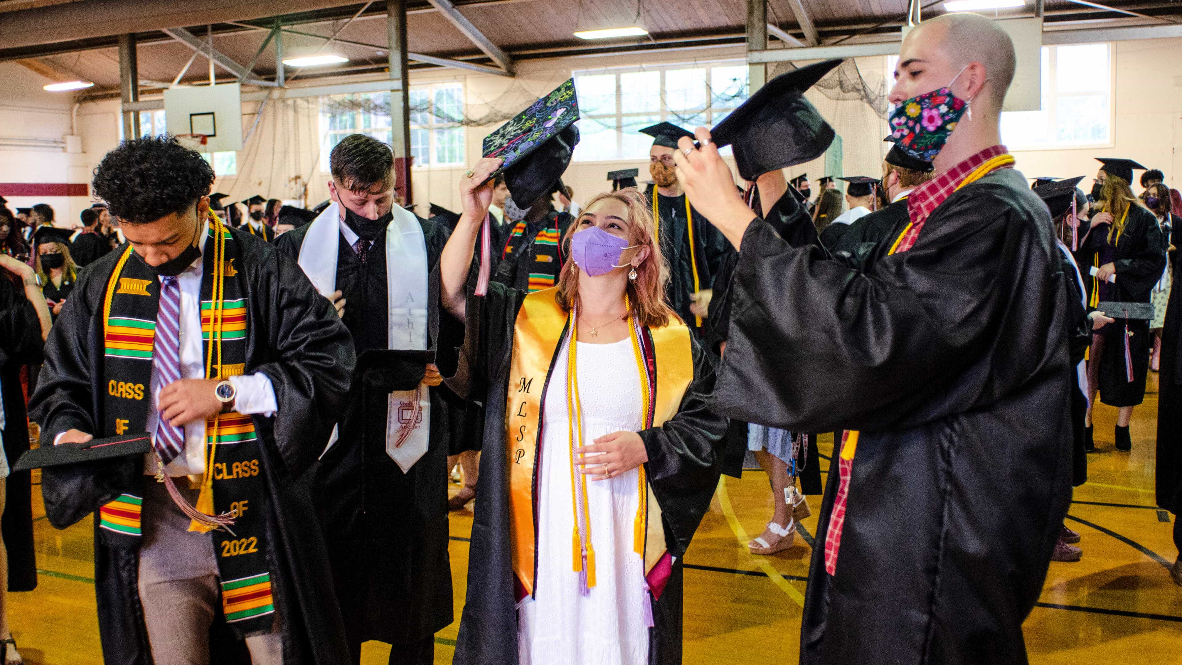 Students zip up their gowns and put on their caps before Commencement.