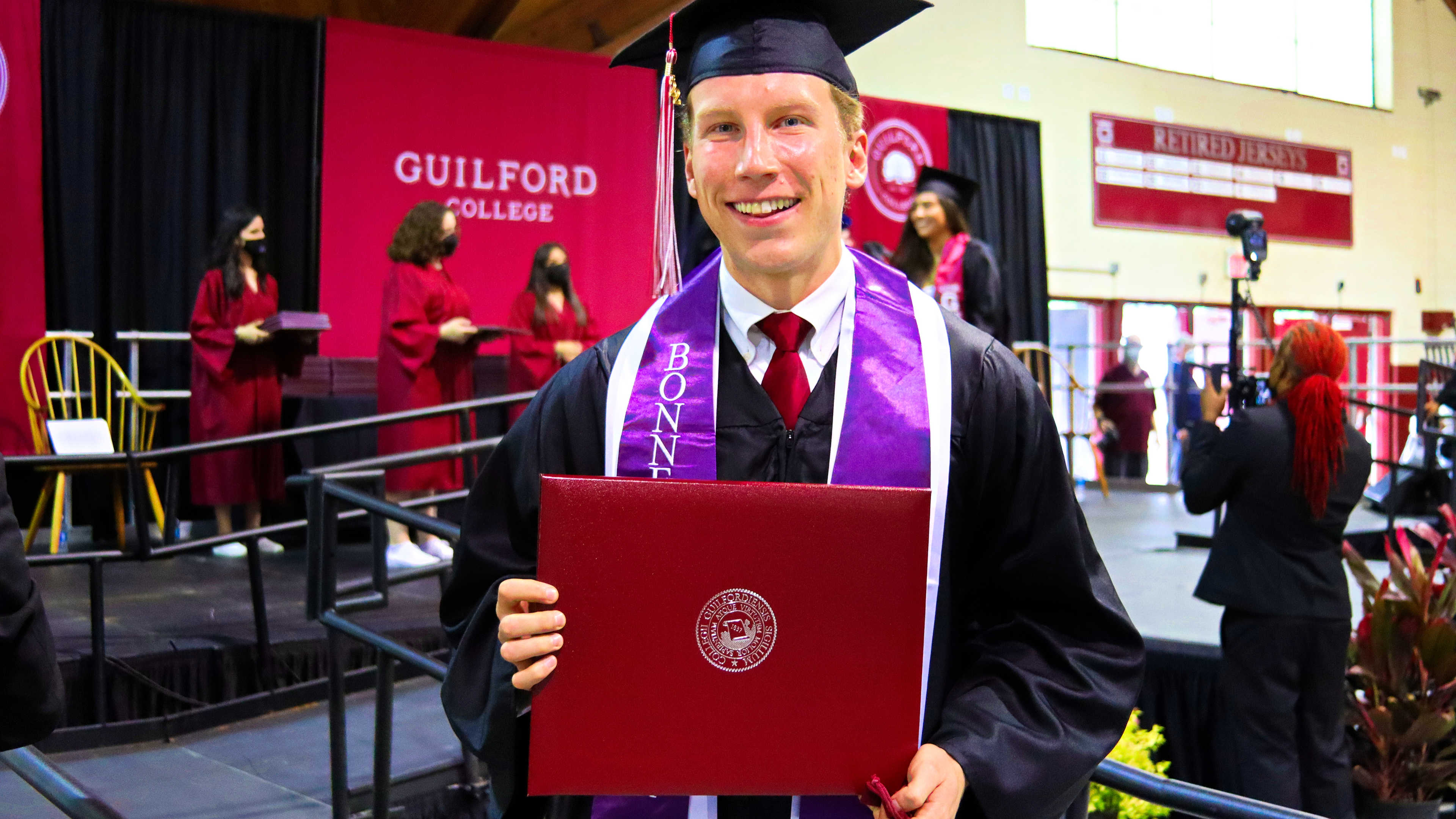 A student shows off their diploma folder after receiving it on stage at Commencement.