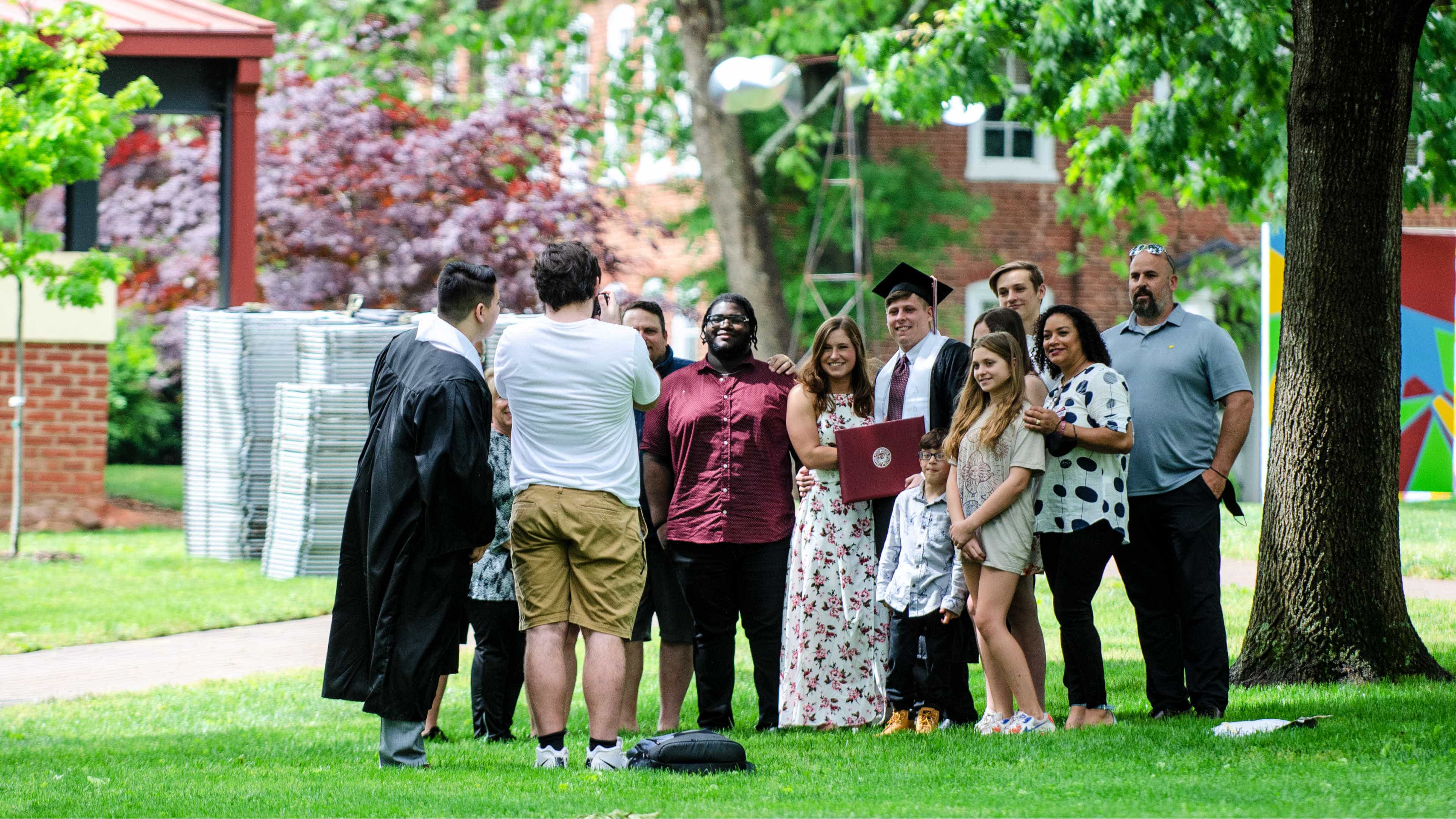 A group of students and family members take a photo outdoors on the Quad after Commencement.