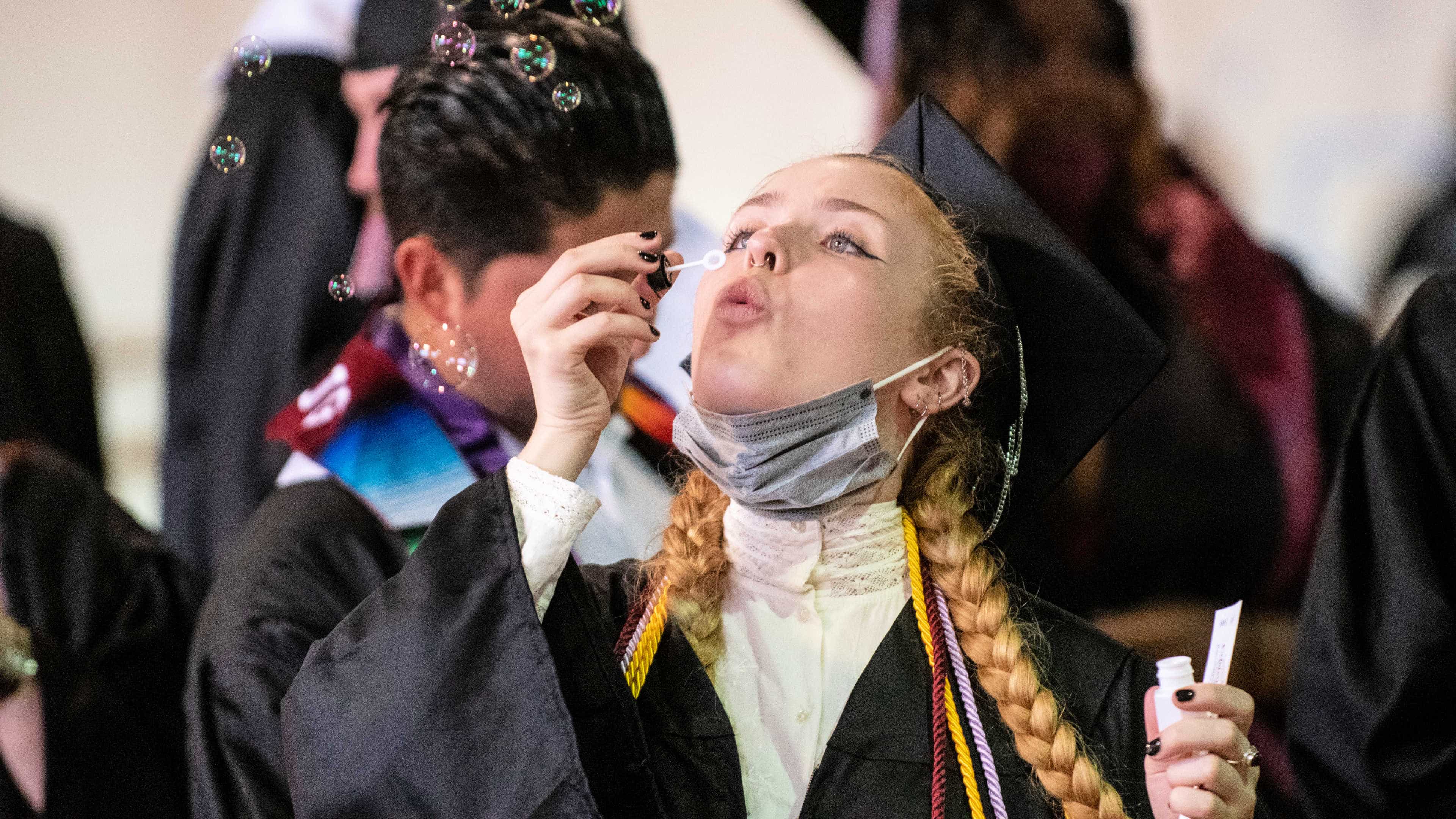A student blows bubbles while the crowd waits to line up to attend Commencement.