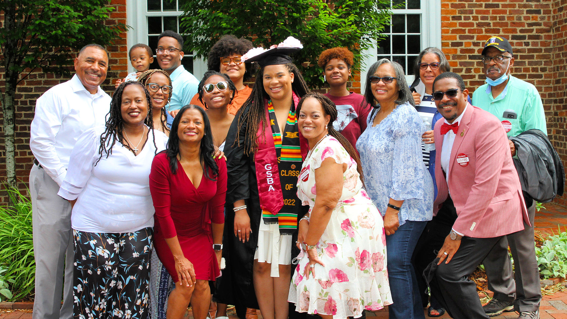 A graduate is surrounded by several friends and family for a photo outdoors after Commencement.