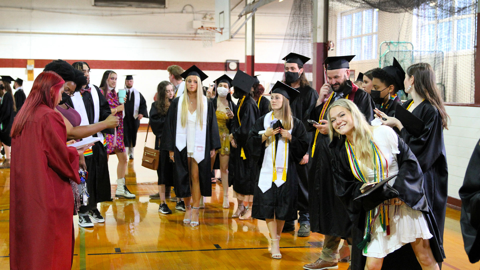 A student leans out of line to give a peace sign to the camera as the crowd lines up to enter Commencement.