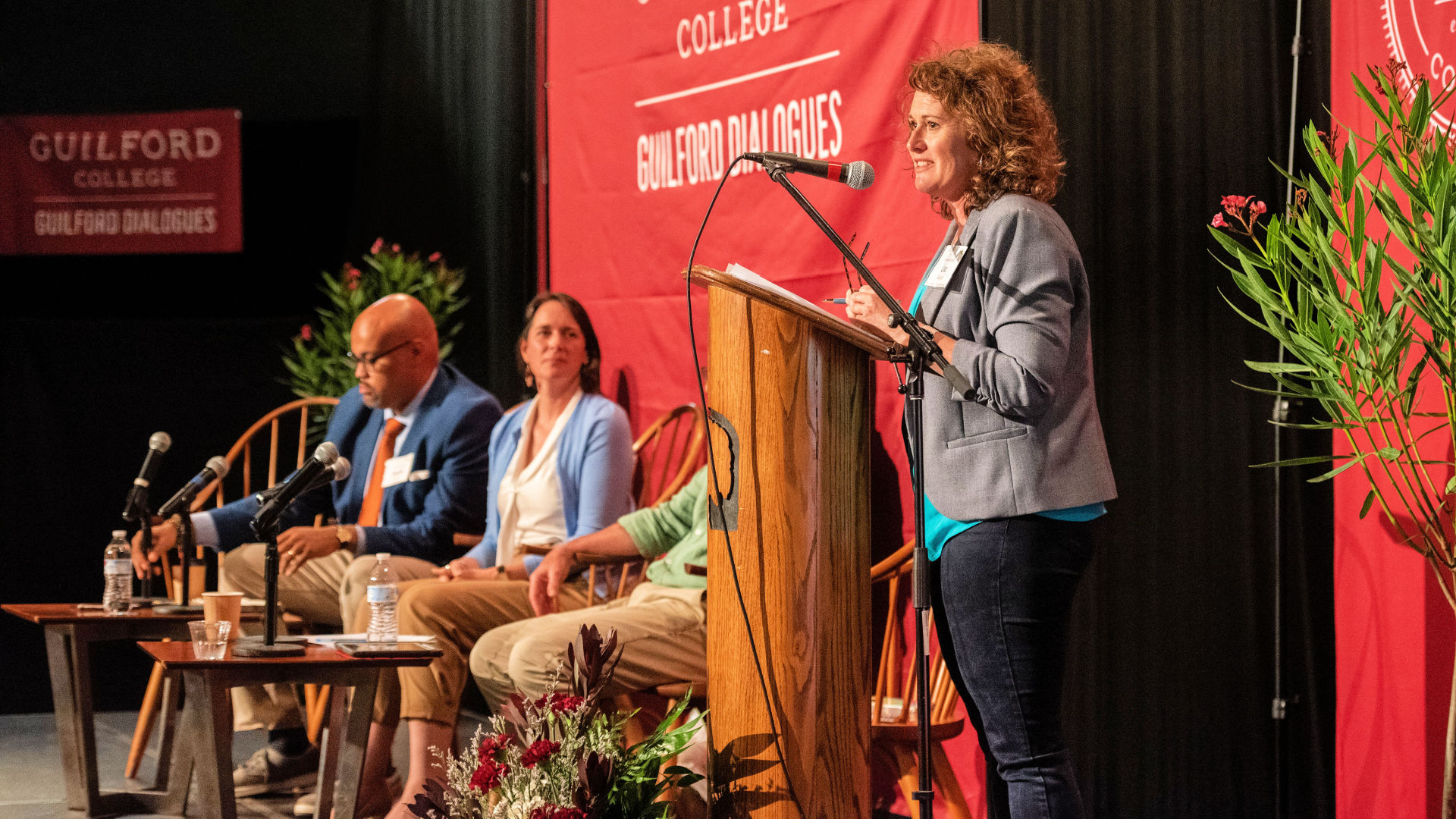 Lisa Hazlett stands at the podium on stage during the Guilford Dialogues.