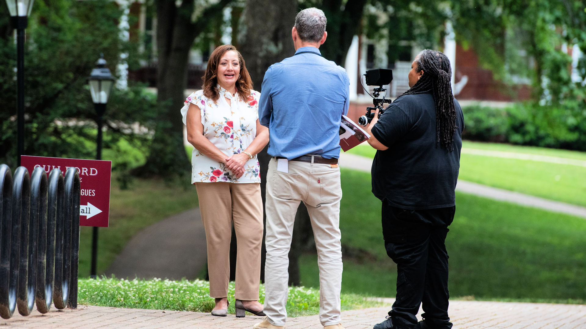 A videographer and writer interview Regina Malveaux outdoors on the Quad during the Guilford Dialogues.