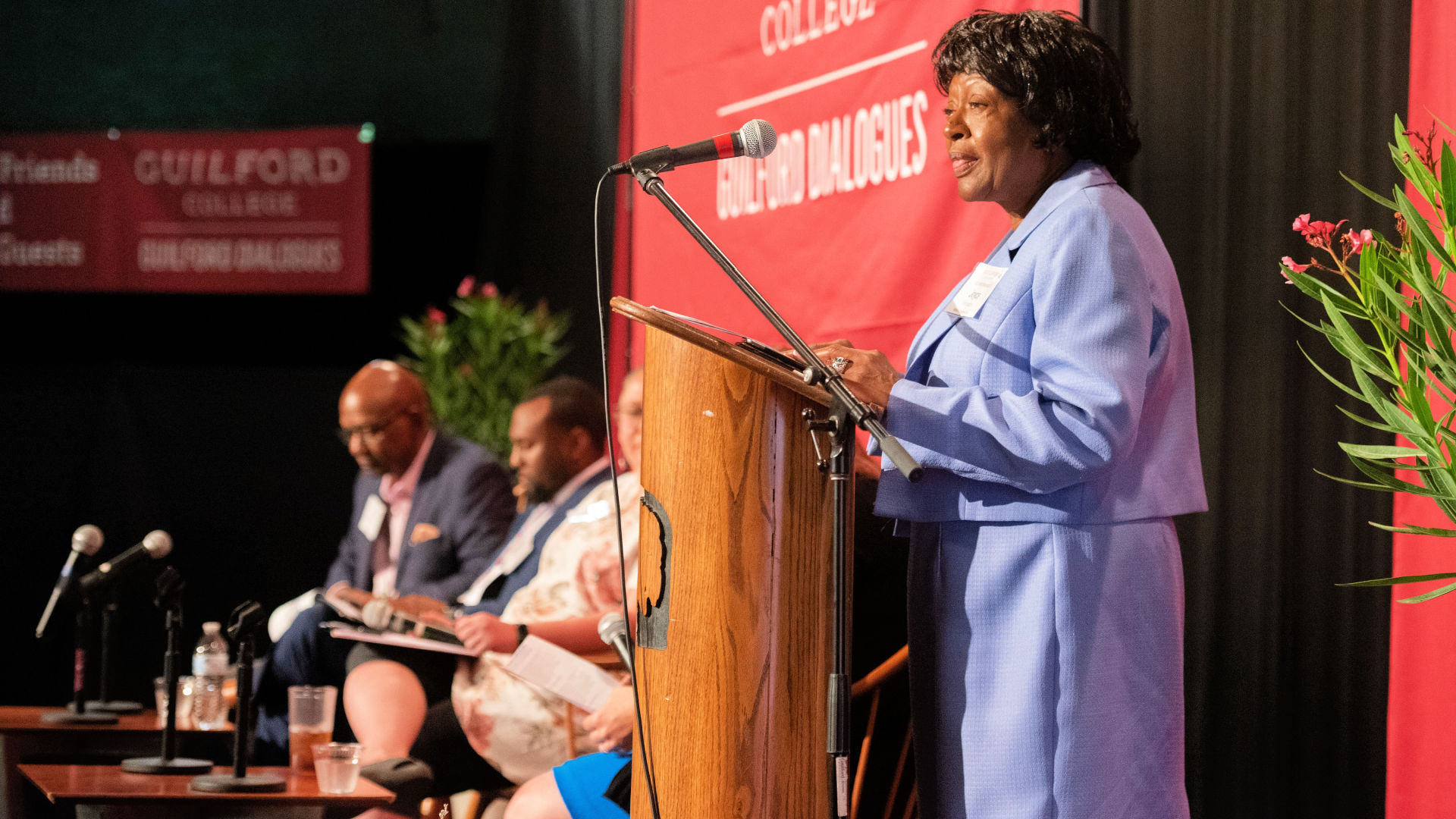Joyce Hobson Johnson speaks from the podium on stage at the Guilford Dialogues.