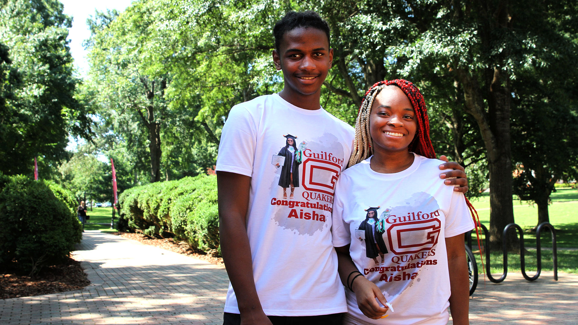 Two students stand on the Quad wearing Congratulatoins, Aisha t-shirts.