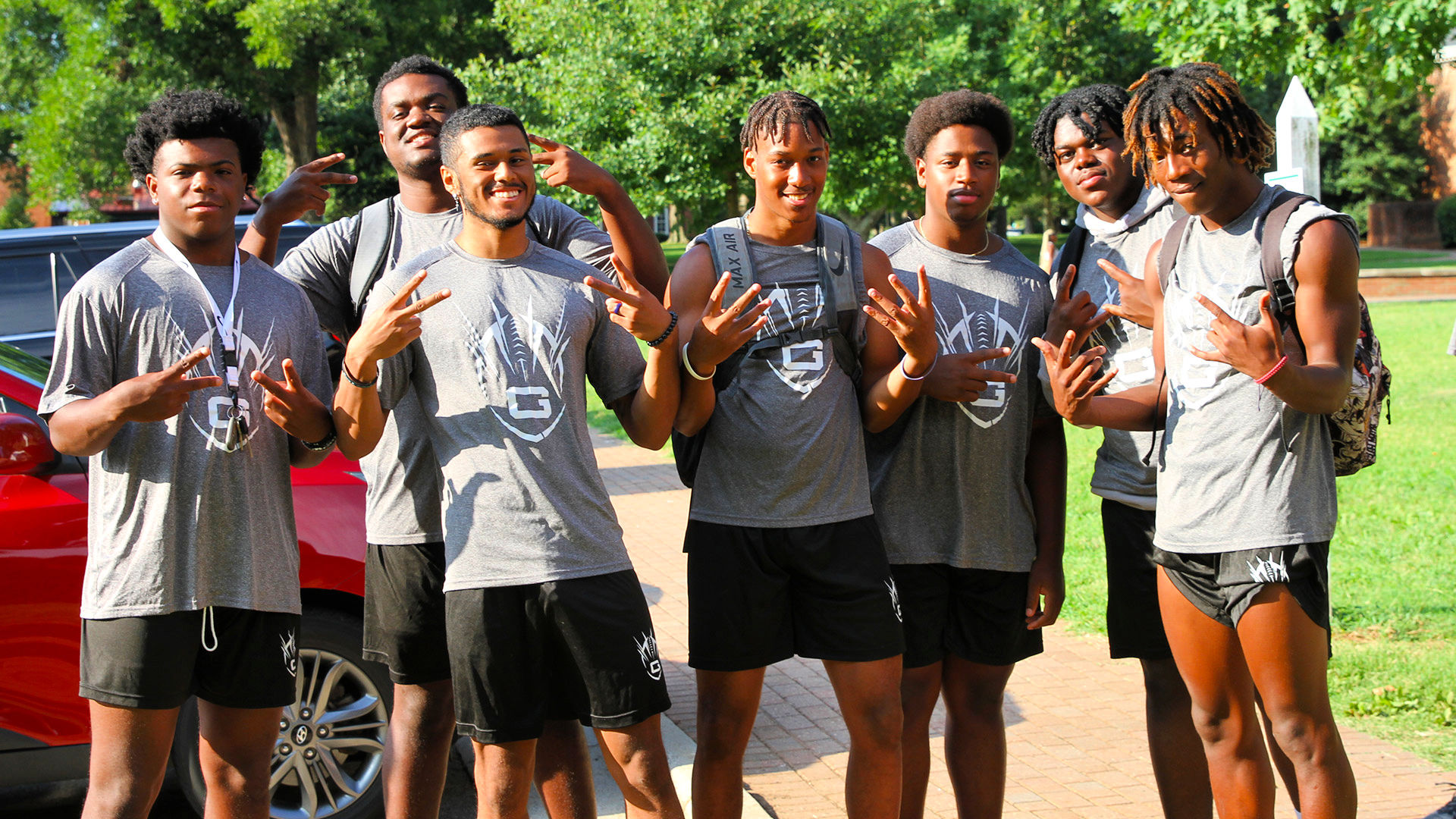 Seven members of Guilford's football team take a group photo while waiting to help new student carry heavy items into res-hall rooms.