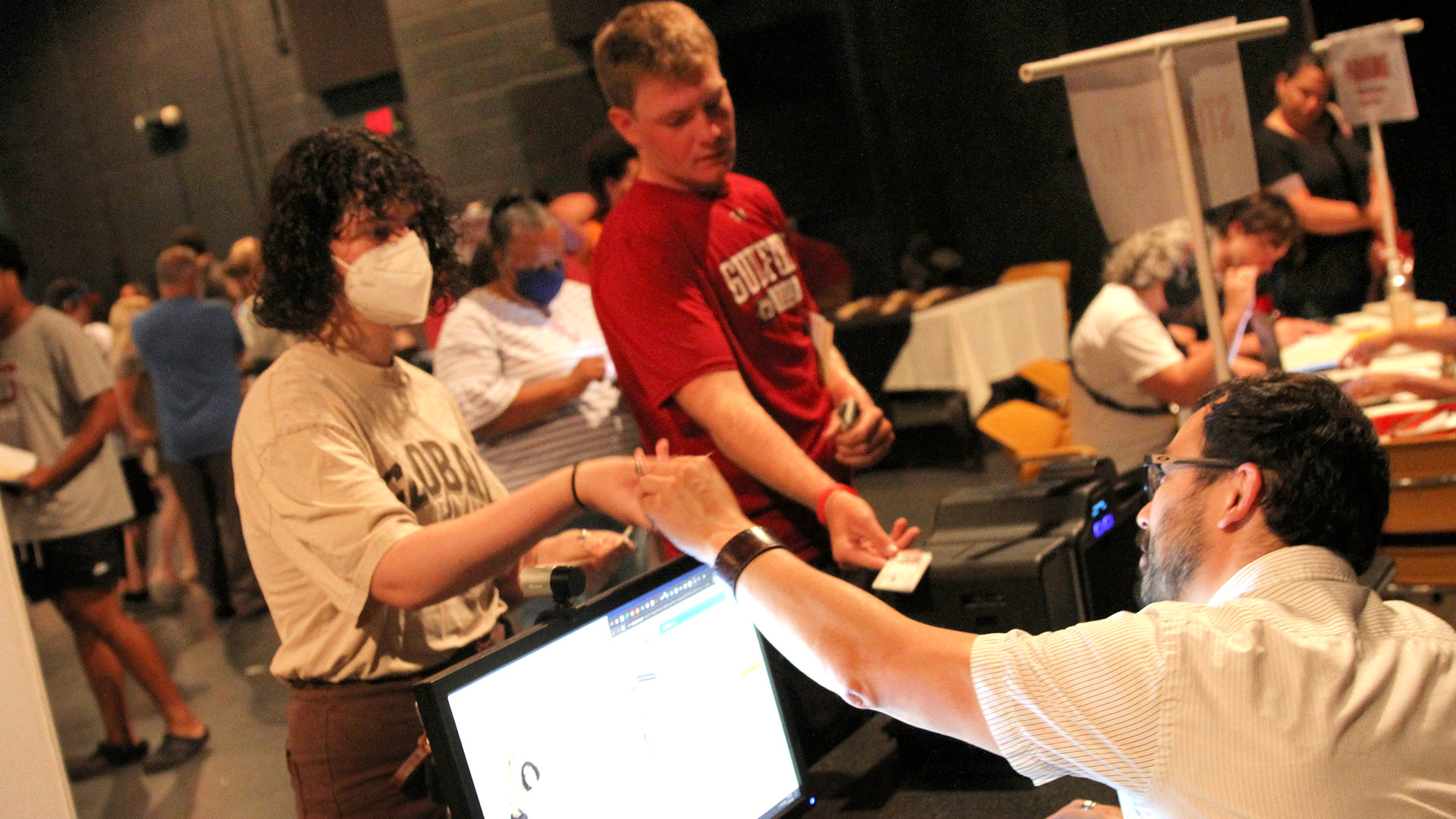 A staff members hands a family member a key, while a student checks hands over their Quaker Card ID.