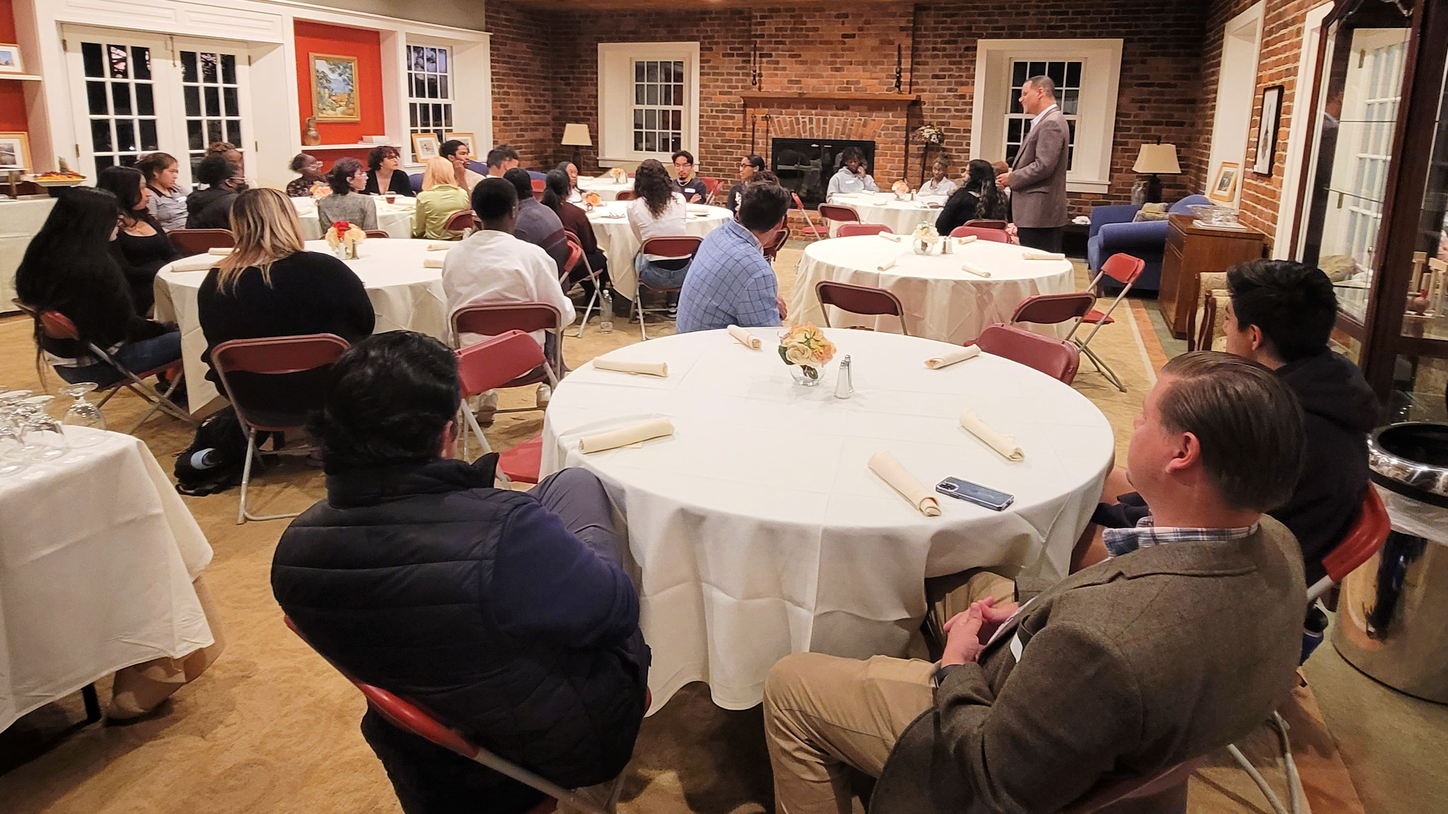 The dining room at Ragsdale House, the President's home, is filled with tables and students while President Kyle addresses first-gen students.