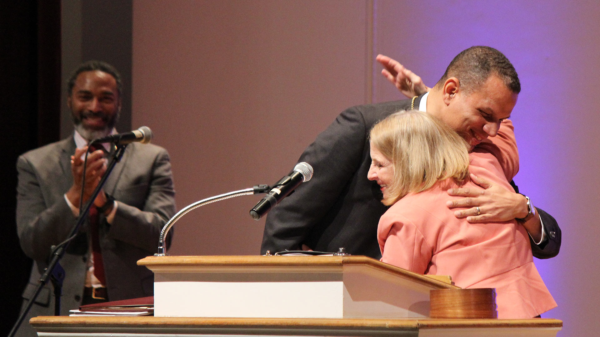 President Kyle Farmbry and Board of Trustees Chair Ione Taylor embrace onstage.