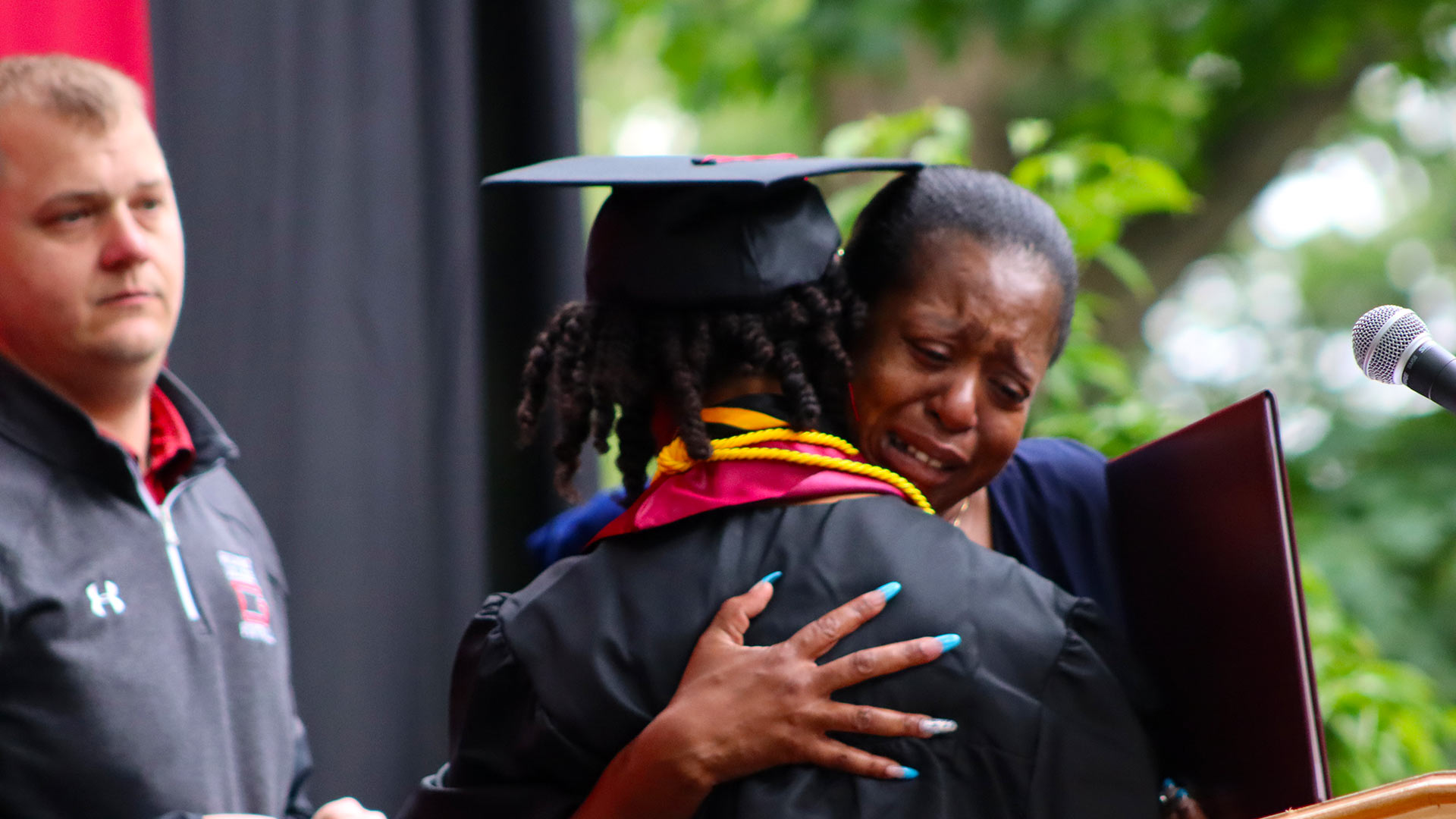 Tinyah Ervin ’23 and Brad Davis ’08 resenting Ahmad Brewington's degree to his family