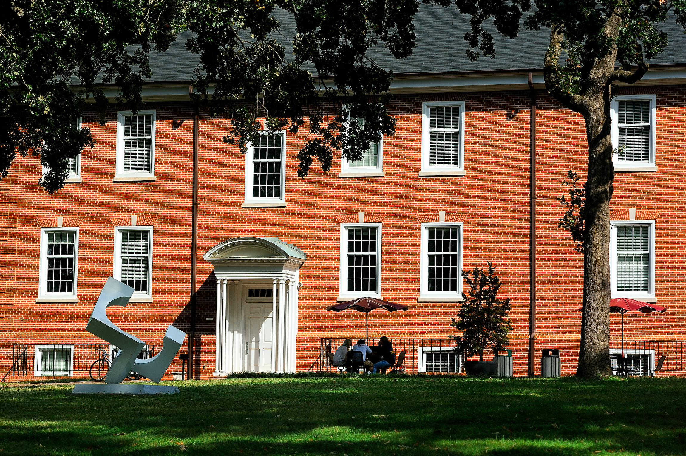 Students sit behind Milner Hall in the afternoon sun.