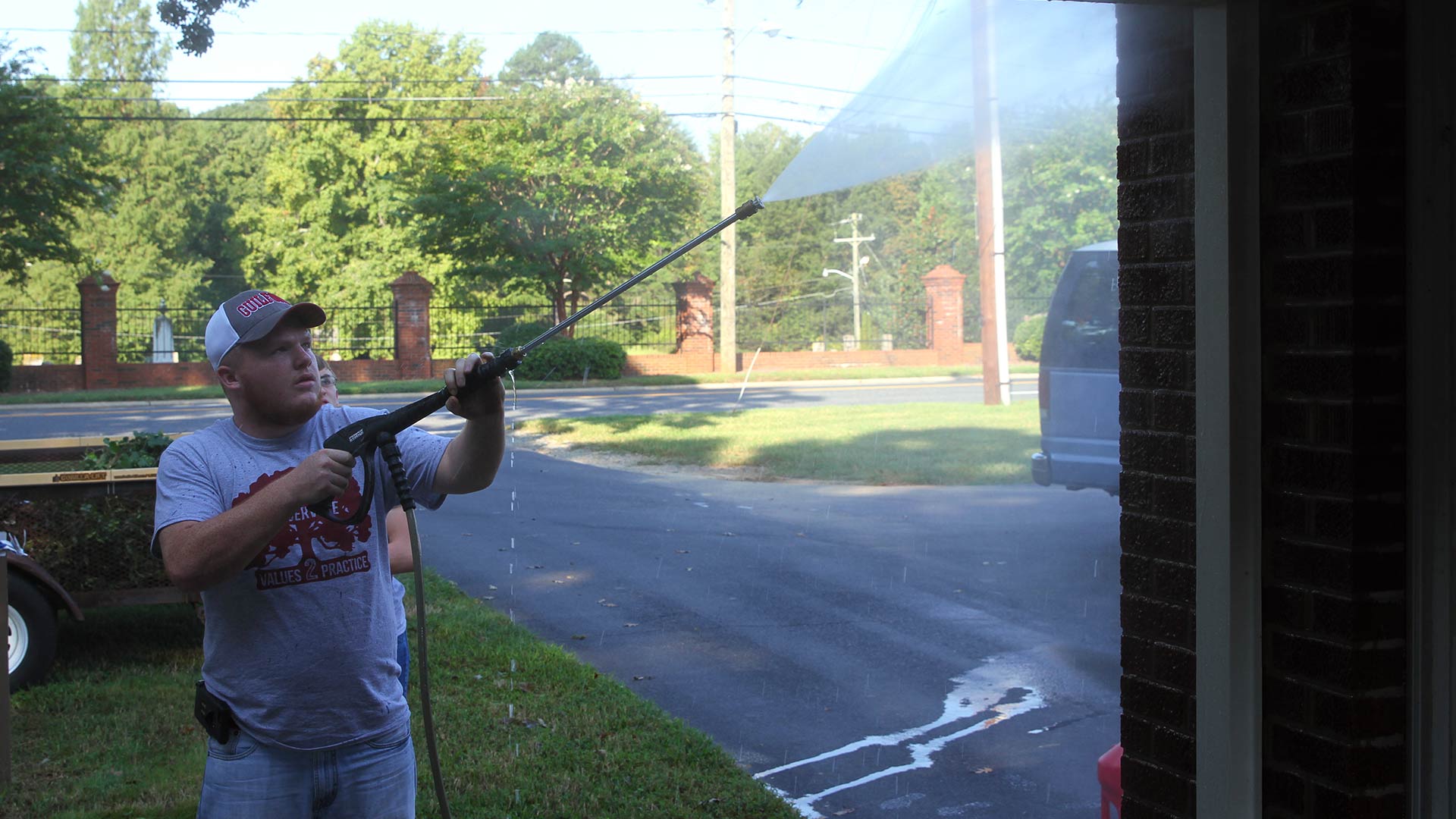 A student power washes a building at Muirs Chapel on Day of Service.