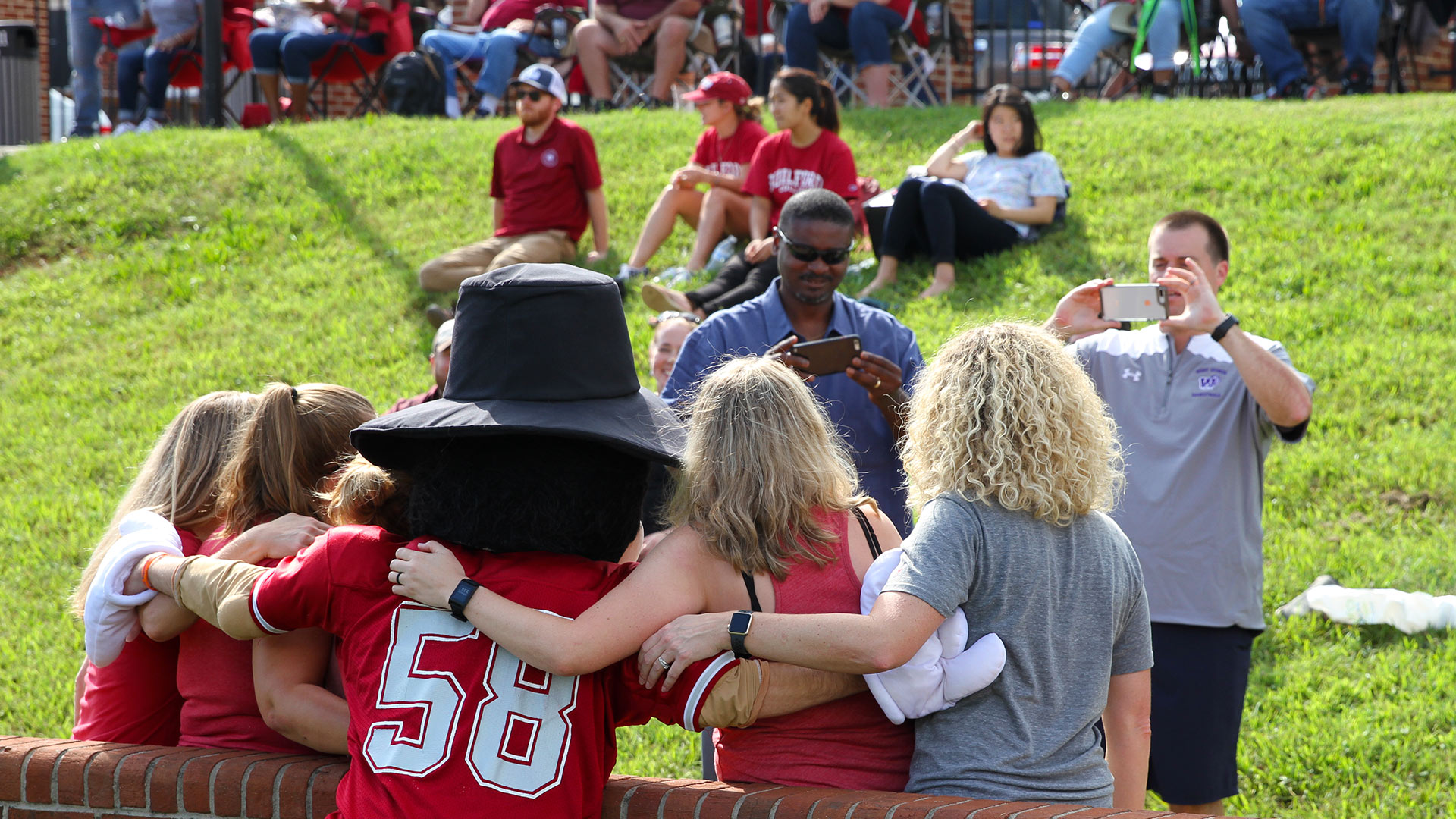 A man takes a photo of friends and family with Nathan the Quaker Man mascot at Homecoming.