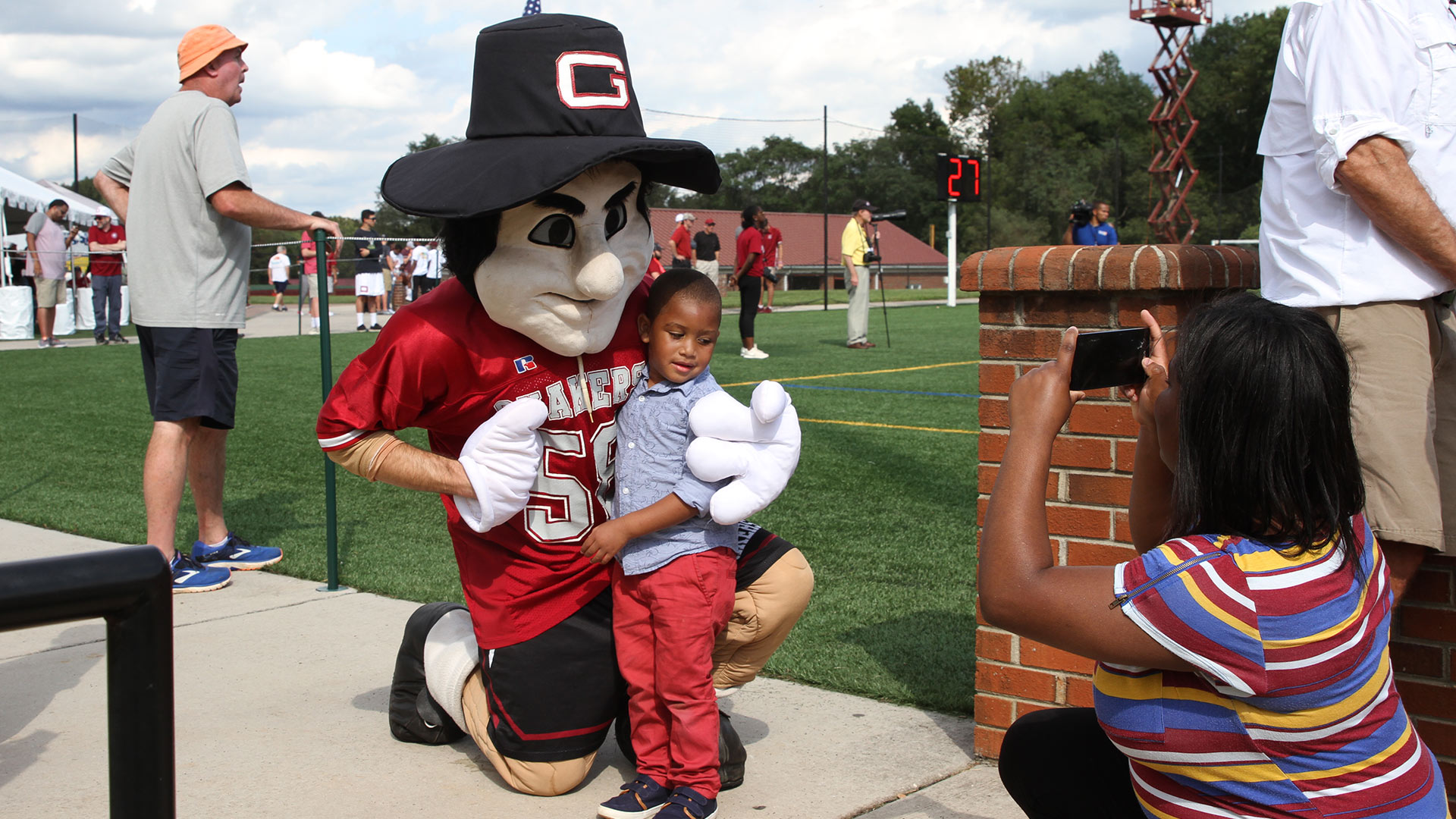 Nathan the Quaker Man mascot takes a photo with a little boy at Homecoming.