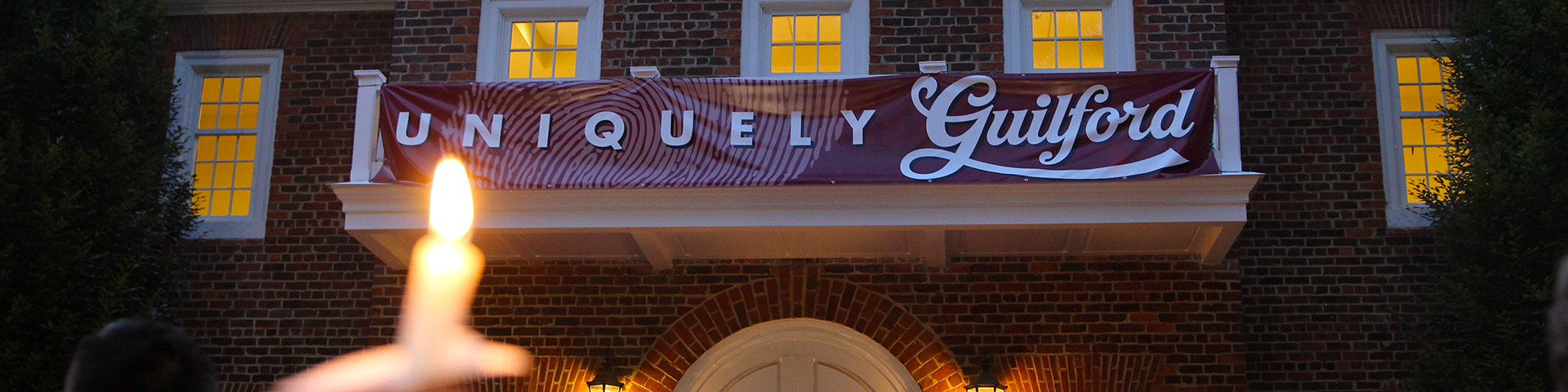 Guilford College Founders Hall with Uniquely Guilford Banner serves as a backdrop for a Passing of the Light ceremony for First-year students