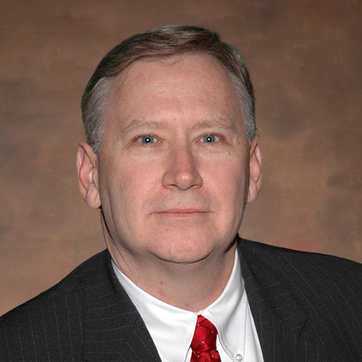 Mike Nichols in a dark suit, white shirt and red tie