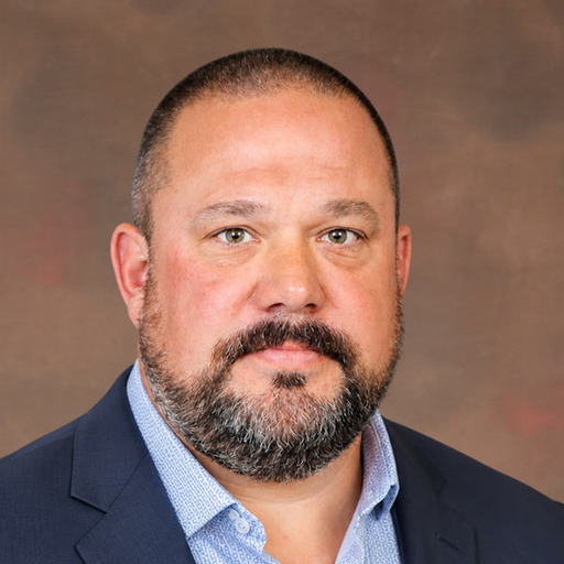 Brad Stewart in a blue blazer in front of a brown background