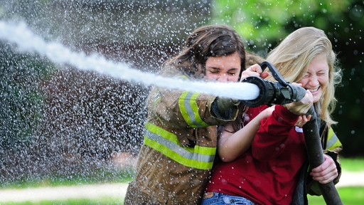 Two students operate a fire hose during Guilford College fire safety day.