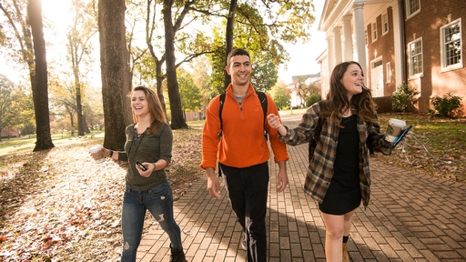 Guilford College students walk through campus with coffee