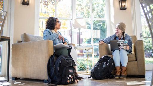 Two students chat between classes while sitting in the Binford Hall Orangerie.