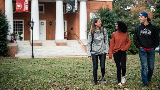 Three students walk together in front of New Garden Hall.