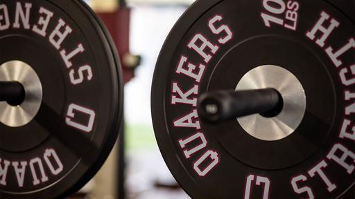 Weights branded with Quakers are stacked in the weight room.