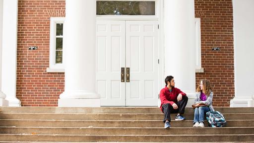 Two students sit on the steps of King Hall.